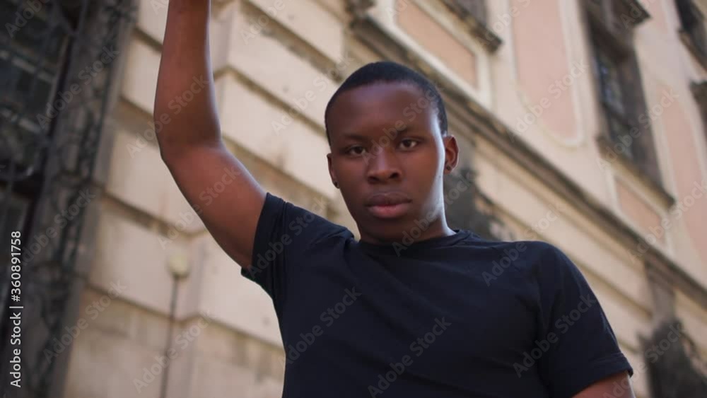 A young African American man protests against police violence and racism. Close portrait of a black man with his fist raised up. Black lives matter A young African American man protests against police violence and racism. Close portrait of a black man with his fist raised up. Black lives matter