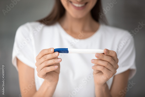 Close up of happy healthy female holding plastic ovulation test with positive pregnancy confirmation results  excited young woman get pregnant having a baby  future maternity  fertility concept