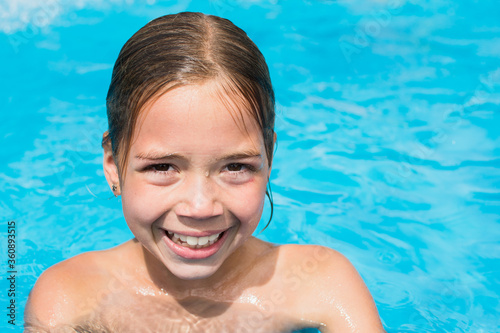 Pretty young girl in the water, kid in swimming pool is smiling