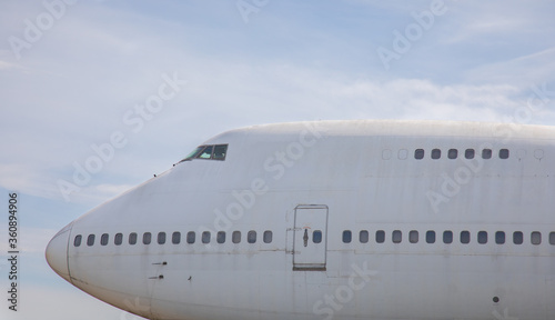 Close-up and high-view shot of airplane's head part is under beautiful blue sky background which has been used for flight service for long time showing water stain and rust on the metal surface.