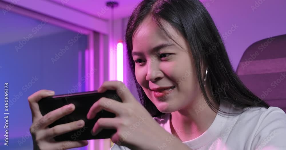 Excited young asian professional cybersport gamer play mobile game by smartphone on eSport tournament online in colorful neon lights room. Having fun, enjoy happy expression.
Excited young asian professional cybersport gamer play mobile game by smartphone on eSport tournament online in colorful neon lights room. Having fun, enjoy happy expression.