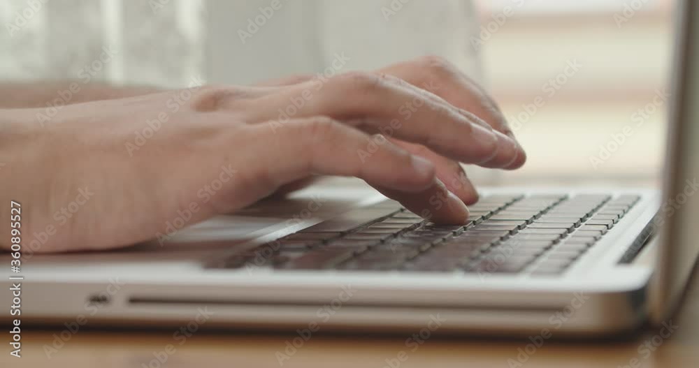 Hands of a man typing text on a beech laptop keyboard. Person sitting at the wooden desk Working He, types, writes emails, Surfs the Internet, Designs Software Hands of a man typing text on a beech laptop keyboard. Person sitting at the wooden desk Working He, types, writes emails, Surfs the Internet, Designs Software