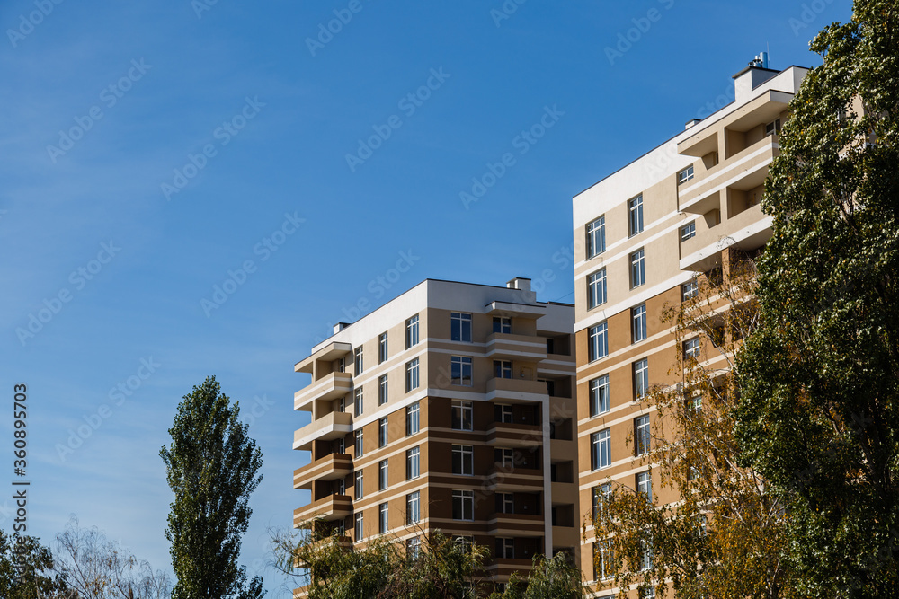 New-constructed unfinished multi-storey residential building. multi-storey residential house in brown and beige colors. Modern residential construction. Residential fund. Building on background of sky