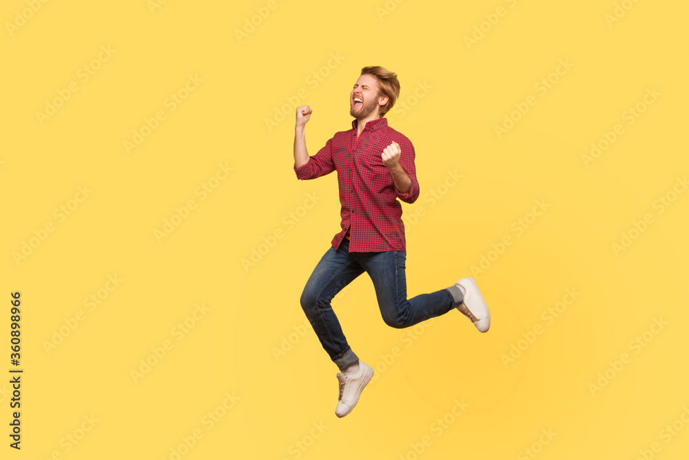 Enthusiastic overjoyed victorious guy in casual outfit jumping high trampoline, flying in air shouting for joy, celebrating victory. Life people energy concept. full length studio shot isolated