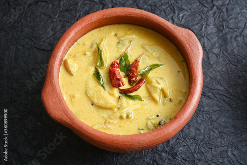 Traditional yellow mango curry or Mampazha Pulissery sweet and sour dish Kerala India . Made from organic raw ripe mango, coconut milk, seasoned with curry leaves, mustard, Indian red Kashmir chilli. photo