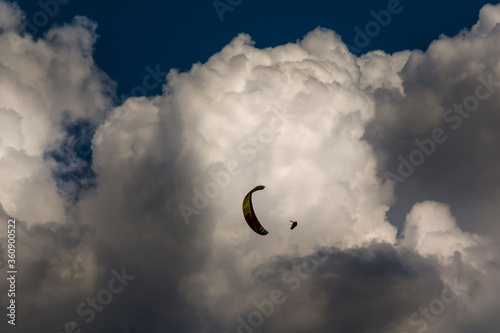 Extreme paraglider flying against a white huge cloud. Spiral dive trick in the air