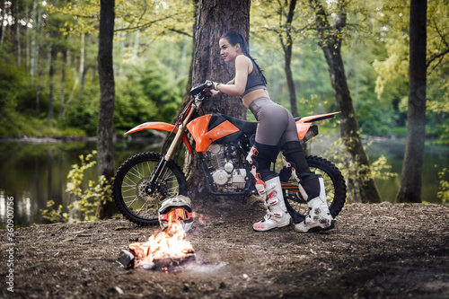 Canvas Print Beautiful young female racer wearing motocross outfit with semi naked torso lean