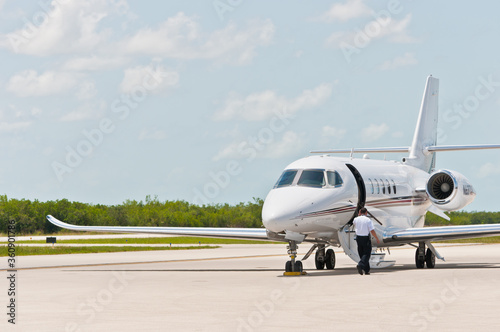 Front view far distance, of an executive, private jet, aircraft, with engines warming up, before taking off and the door, stairs, for boarding, on tropical, island, airstrip, on the gulf of Mexico, 