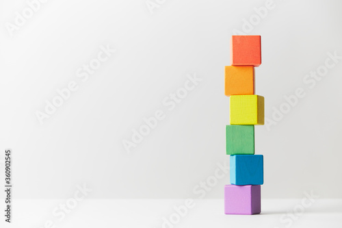 Wooden toys concept. Tower of wooden blocks in colours of the gay pride rainbow flag. Tower unevenly built.