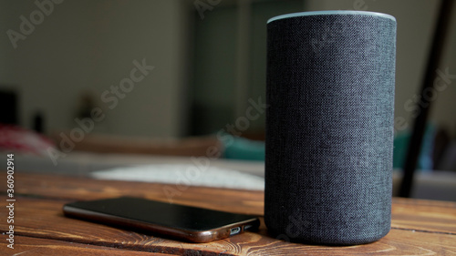 Dark grey Black Amazon Alexa Echo and smart phone on the wooden table in a living room,