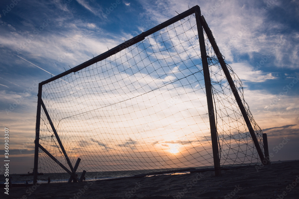 Silhouette of an empty soccer goal on a beach with a beautiful sunset in the background Silhouette of an empty soccer goal on a beach with a beautiful sunset in the background