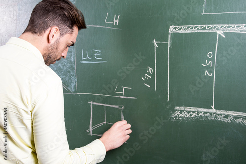 Persona escribiendo con tiza en una pizarra contenido de arquitectura