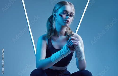 Tela strong beautiful girl with blonde hair, confident look, fists in protective boxi