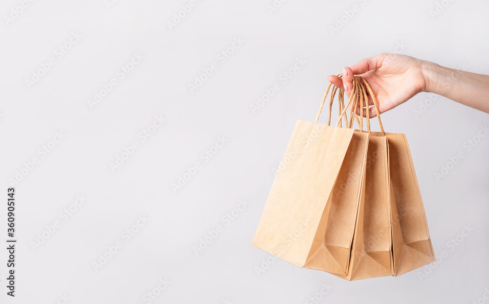 woman hand carrying a bunch of shopping bags over gray background