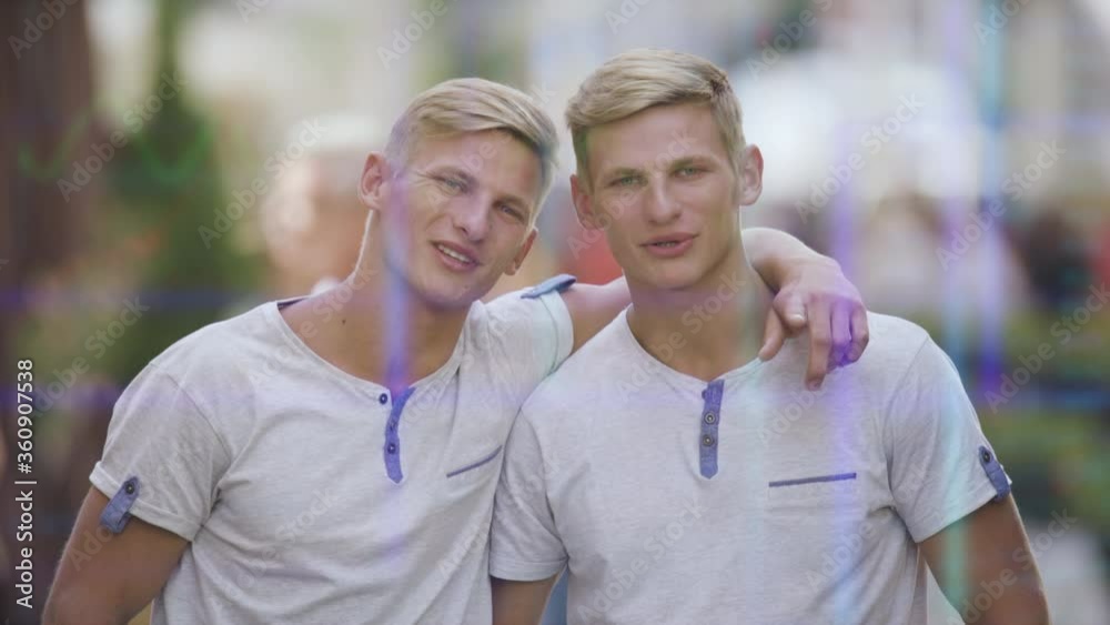 The smiling brothers twins stand on the crowded street on holographic background The smiling brothers twins stand on the crowded street on holographic background