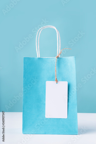 blue shopping bag with a blank white tag on white table