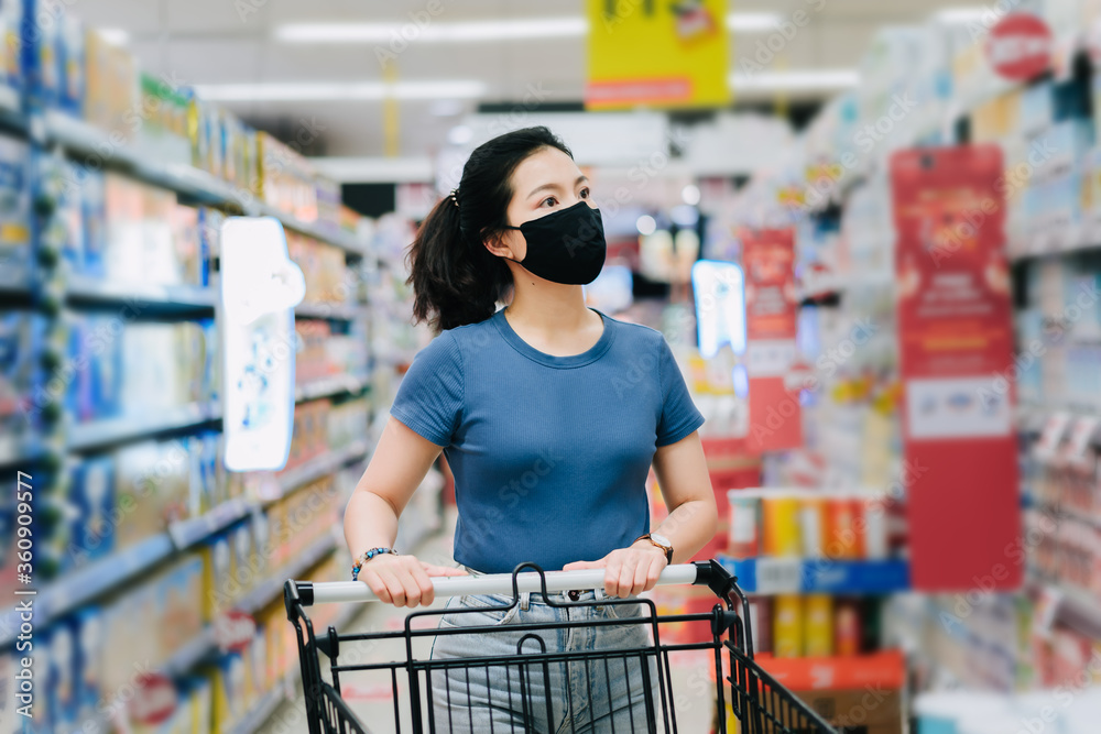 Young Asian woman wear a black face mask are shopping in supermarket