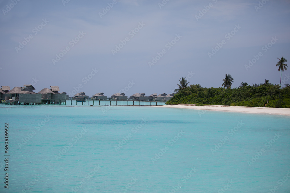 Maldivian water villas and island seen from turquoise ocean 