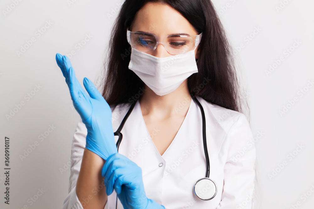 Female doctor in a white coat wears medical gloves Female doctor in a white coat wears medical gloves