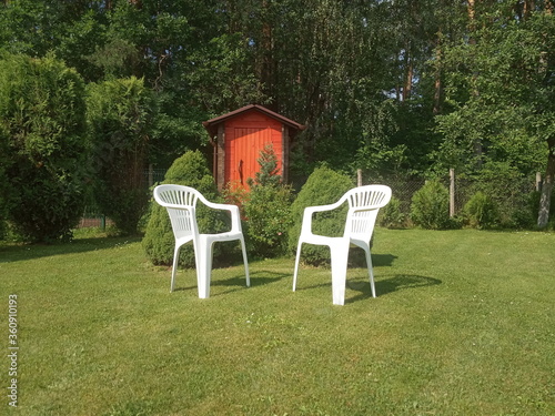 two white plastic chairs stand on the lawn, garden furniture
