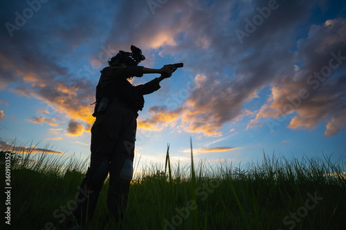 Silhouette of female soldier in high grass land on the sunset background , twilight landscape silhouette soldiers