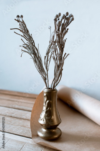 dry lots of flower in a golden vase on a wooden table with craft paper