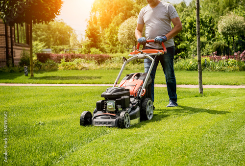 Gardener mowing the lawn. Landscape design. Green background