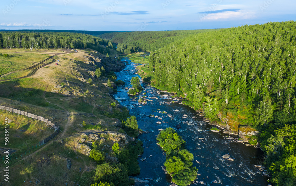 soft sun rays in evening over beautiful valley with a mountain river and many rapids. Ural, Russia, view from drone.
