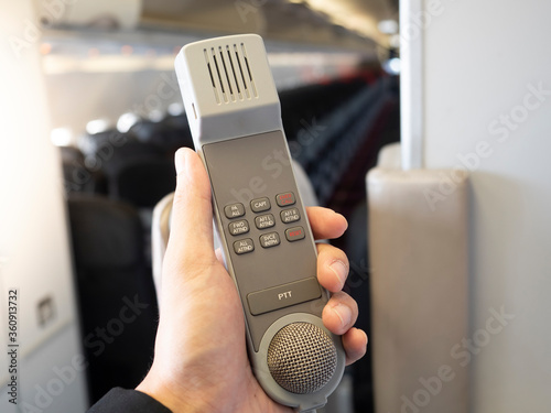 Male cabin crew holding interphone in aircraft cabin.  photo