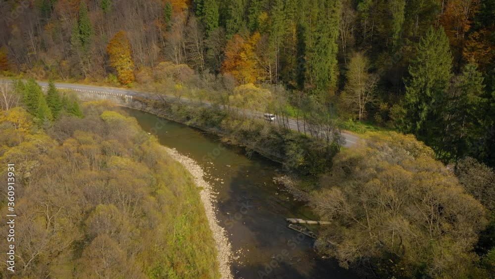 View from the height on the autumn landscape - river, forest on a mountainside, car on the road