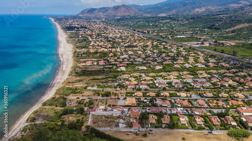Aerial view of the Villa in Campofelice di Roccella in Sicily, under a beautiful sunny sky, with swimming pools and trees.