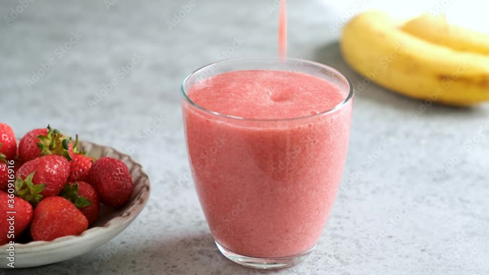 Pouring strawberry smoothie in drinking glass. Raw vegan strawberry smoothie Pouring strawberry smoothie in drinking glass. Raw vegan strawberry smoothie