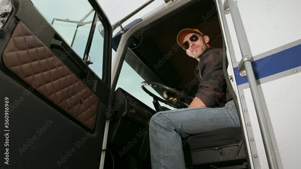 Man Truck Operator Sitting Inside Of Vehicle Cabin Communicating With Person On CB Radio. Man Truck Operator Sitting Inside Of Vehicle Cabin Communicating With Person On CB Radio.