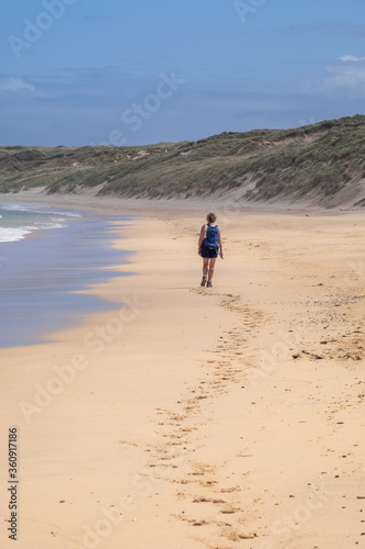 Woman walking on a beach in cornwall hayle with footprints 