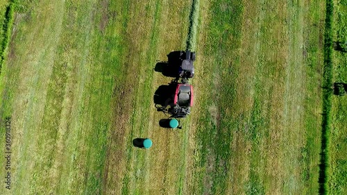 Schwarzer Treker mit einer roten Stroh Festkammerpresse bei der Strohernte auf einem gemähten Feld