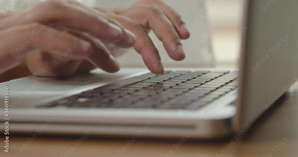 Hands of a man typing text on a beech laptop keyboard. Person sitting at the wooden desk Working He, types, writes emails, Surfs the Internet, Designs Software Hands of a man typing text on a beech laptop keyboard. Person sitting at the wooden desk Working He, types, writes emails, Surfs the Internet, Designs Software