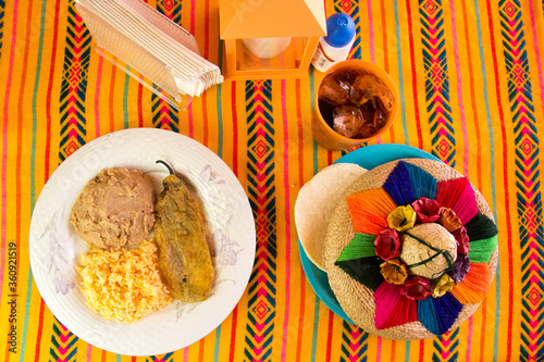 platillo de chile relleno con arroz y frijoles refritos en una mesa decorada mexicana en un restaurante mexicano 