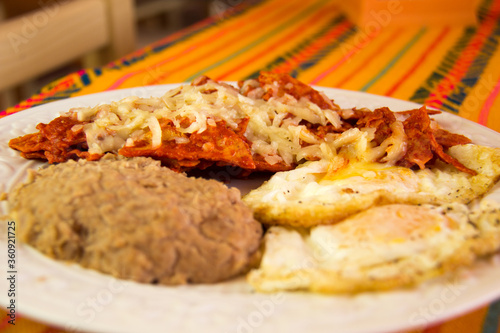 RED CHILAQUILES WITH STARRY EGGS AND REFRITTED BEANS IN A MEXICAN RESTAURANT