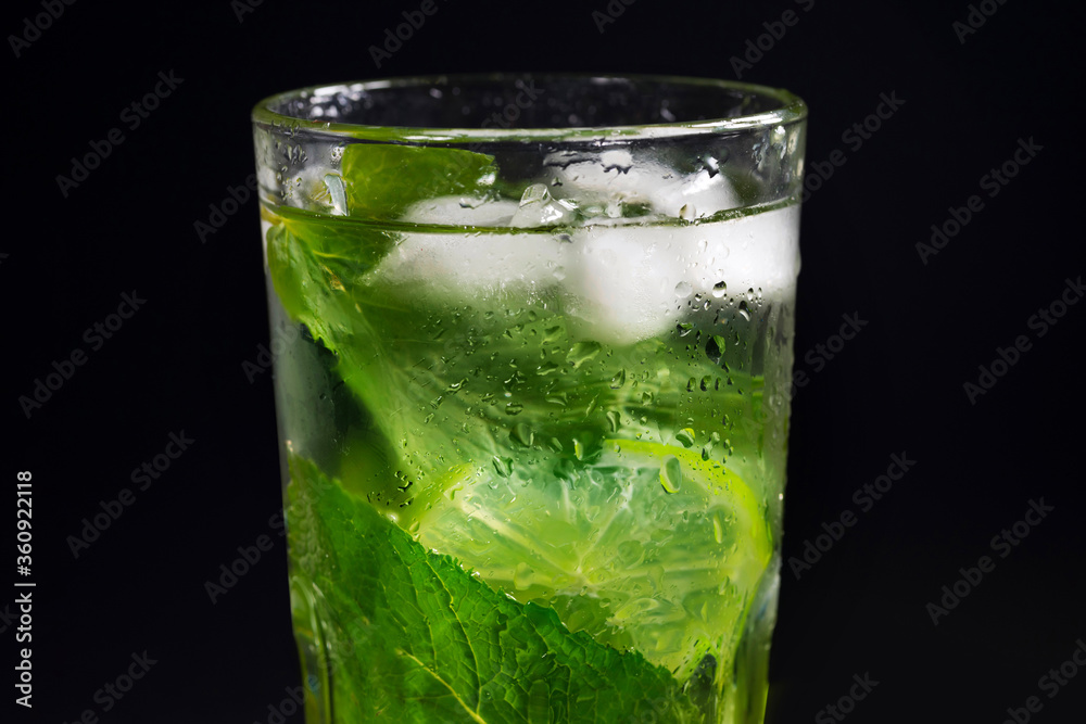 Mojito refreshing cocktail with mint leaves, lime and ice on a black background. Mojito refreshing cocktail with mint leaves, lime and ice on a black background.