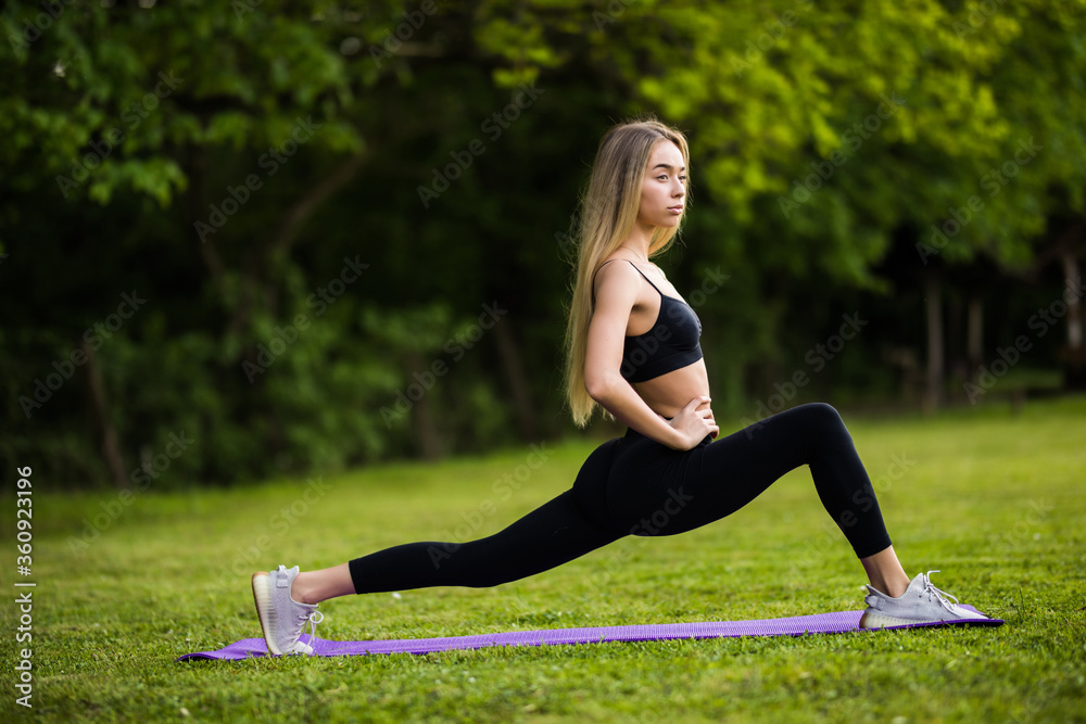 Fototapeta premium Young woman stretching her legs at the park at early in the morning.