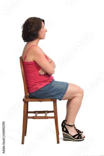 side view woman in skirt sitting on white background, arms crossed