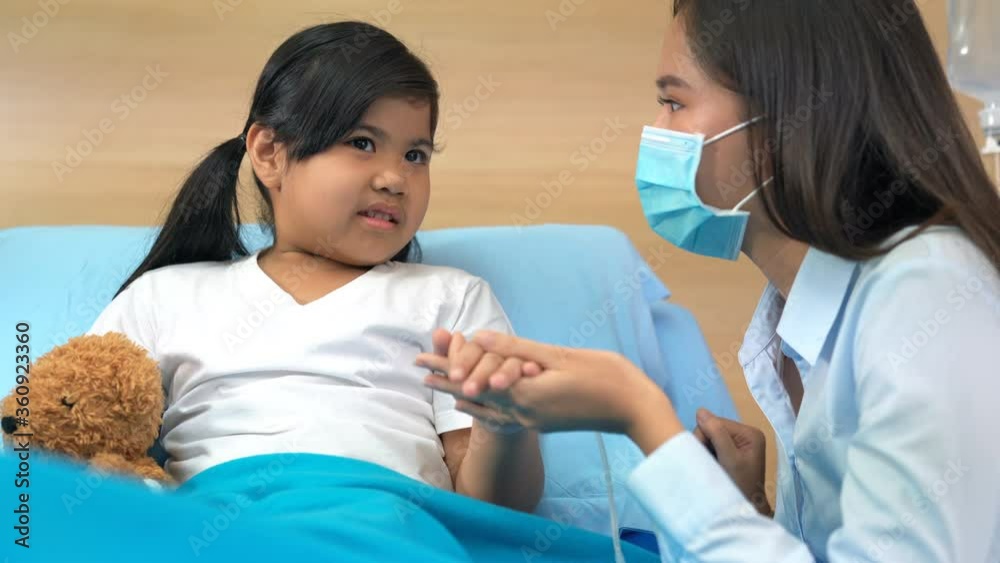 Worried mother taking care of a little girl with sick and a bone splint broken arm in hospital bed with teddy bear. Worried mother taking care of a little girl with sick and a bone splint broken arm in hospital bed with teddy bear.