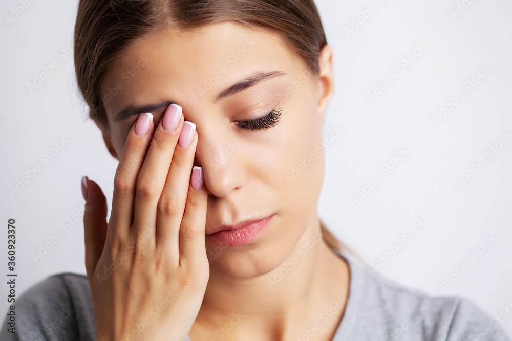 Exhausted young woman suffering severe pain from near the eyes Exhausted young woman suffering severe pain from near the eyes