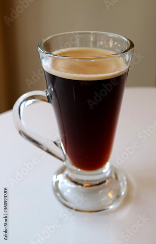 Vertical Image of Hot Black Coffee in a Transparent Glass Isolated on White Table