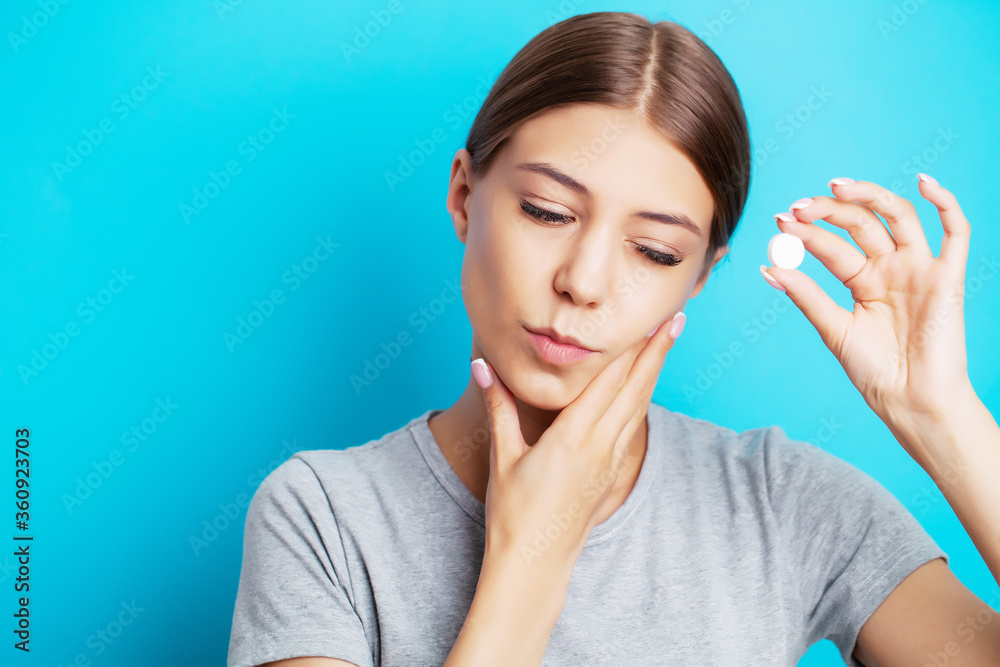 An exhausted woman suffering from toothache takes a painkiller An exhausted woman suffering from toothache takes a painkiller