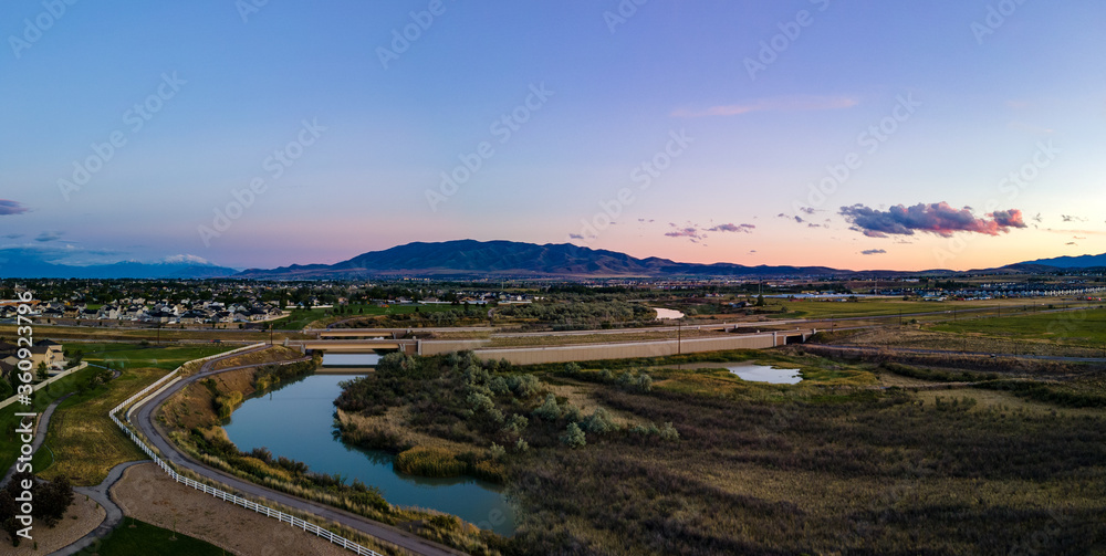 Panoramic view of a river flowing under a highway with a city and mountains inn the distance