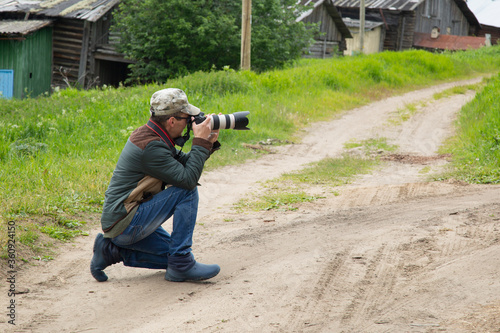 A photographer with a camera takes a landscape on the street.