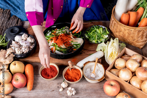 Korean woman is wearing a traditional hanbok, she making Kimchi which is a fermented food preservation of Korean people consisting of many fresh vegetables and fruits