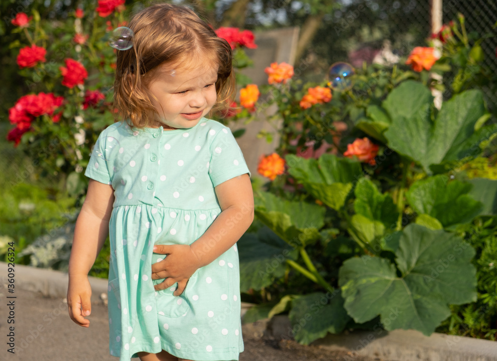toddler girl looking at bubbles background of greenery and roses. summer. space for text toddler girl looking at bubbles background of greenery and roses. summer. space for text