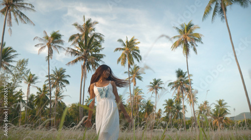 Happy girl shaking hairs among grass filed tropical landscape